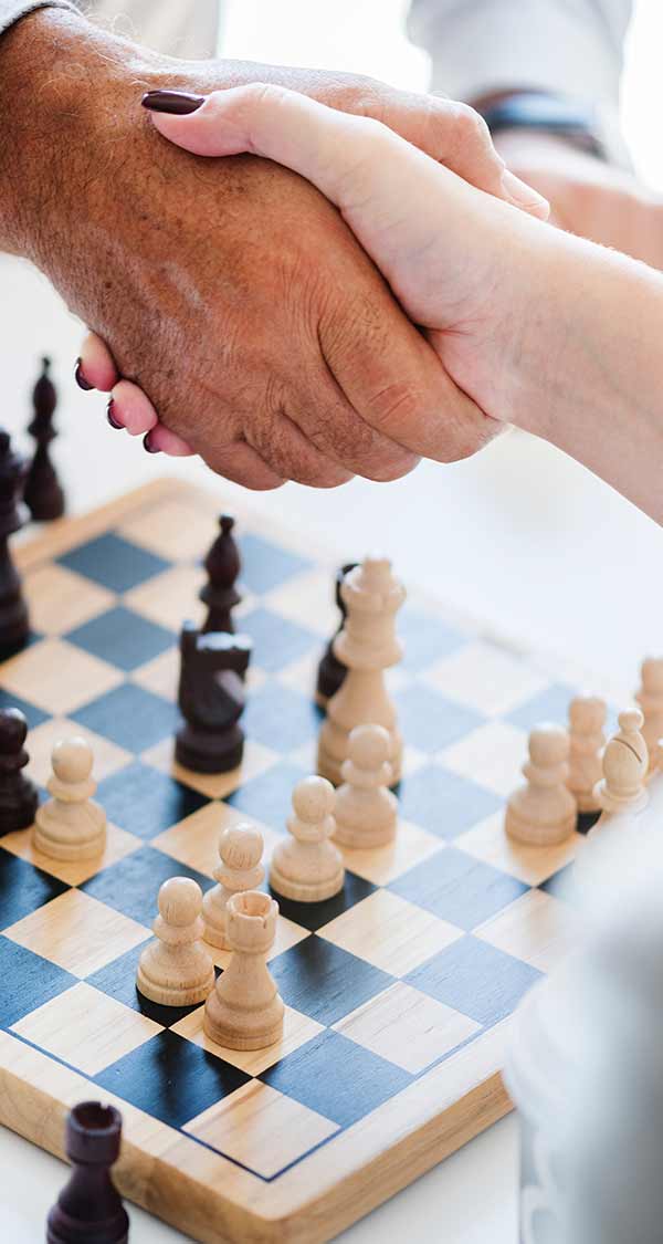 Two people shaking hands over a chess board