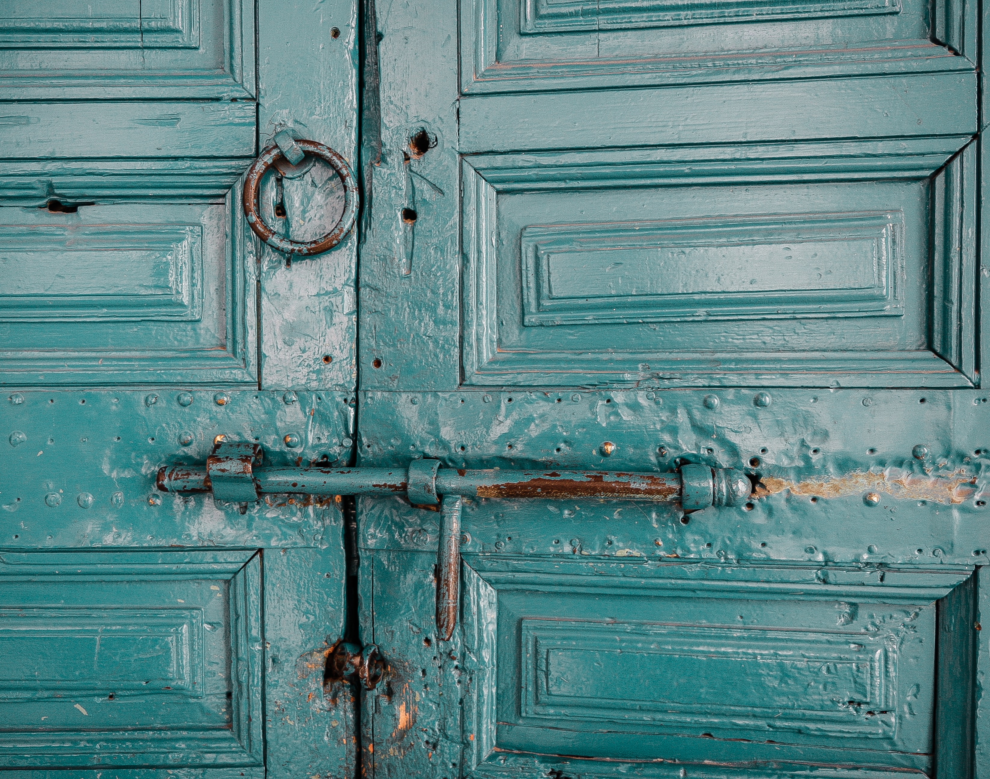 An old green door locked with a bolt.