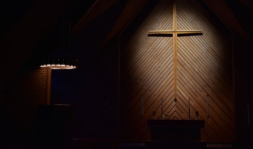 A cross on a wall in a darkly lit church